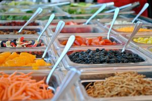Various colored food in salad bar containers with spoons